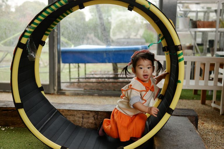 Evoke Clayton, child playing in black tunnel with yellow rim.