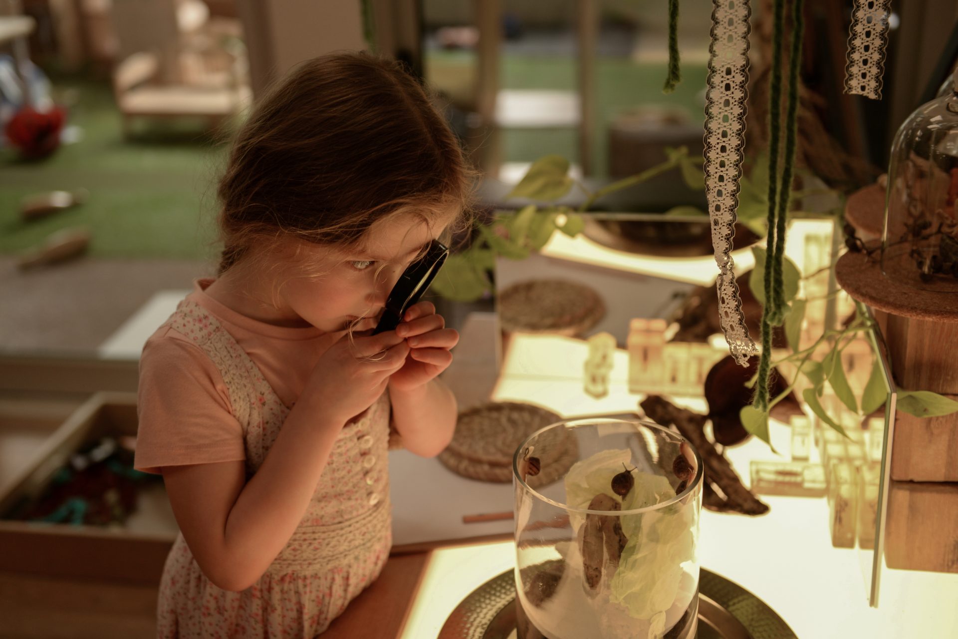 Girl looking through magnifying glass at Evoke Early Learning Albert Park and South Melbourne.
