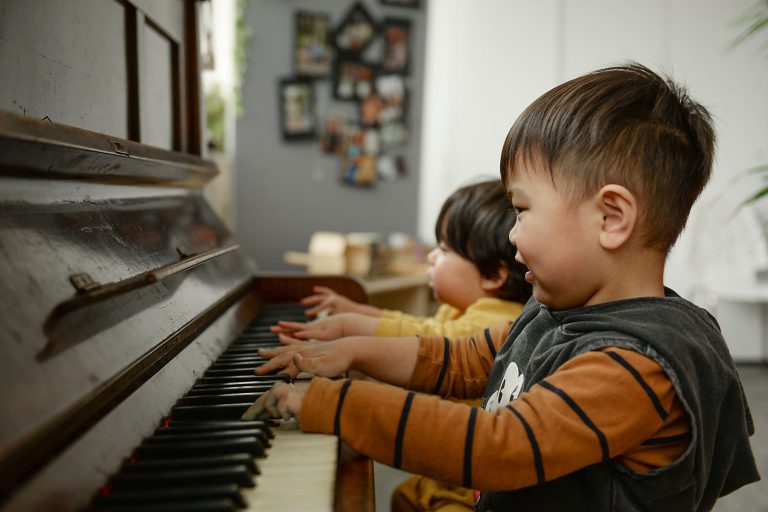 Two kids playing the piano together at Evoke Early Learning Child Care Centre in Albert Park and South Melbourne.