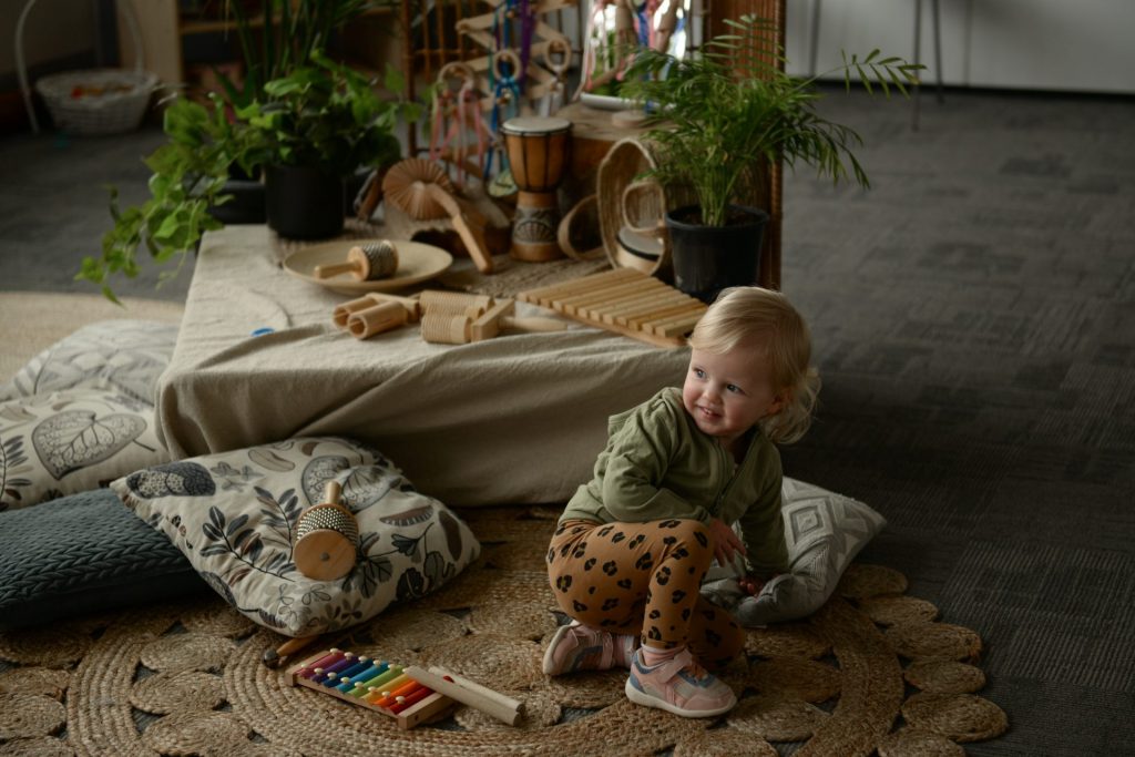 Nursery with baby crawling on floor with cushions and percussion instruments around them